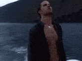 a man is standing on a boat in the water without a shirt on .