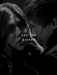 a black and white photo of a man touching a woman 's face with the words " and the mirror " above them .