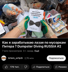 a person holding a book titled dumpster diving russia # 2 in front of a pile of garbage
