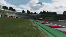 a helicopter is flying over a race track with a yellow car