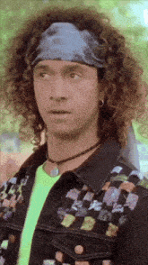 a man with curly hair is wearing a headband and a neon shirt