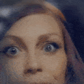 a close up of a woman 's face with a surprised look on her face and purple hair .