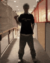 a man wearing a black comme des garçons shirt is standing in a hallway