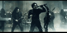 a man is singing into a microphone while a group of people play instruments .
