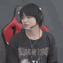 a young man wearing headphones and a necklace is sitting in a red chair .