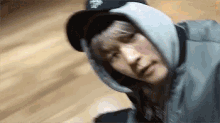 a young man wearing a hat and a hoodie is laying on the floor .