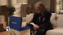a man sits on a couch looking at a box that says playstation 2