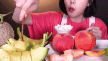 a woman in a red shirt is eating fruit with a fork