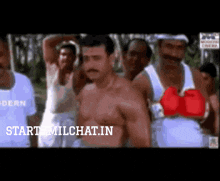 a group of men are standing around a shirtless man wearing boxing gloves with the words start milchat.in on the bottom