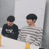 two young men are sitting at a table with bottles of liquid .