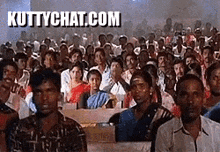 a large group of people are sitting in a room with a sign that says kuttychat.com