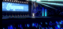 a group of dancers are on a stage with a large screen that says aqours