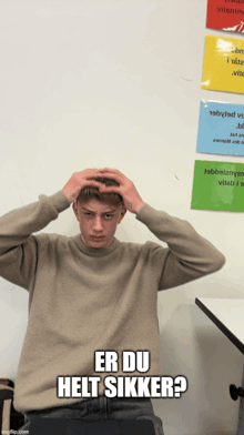 a young man holds his head in front of a sign that says er du helt sikrer