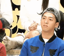 a man wearing a hat and a blue jacket is sitting in front of a woman .