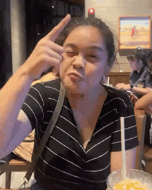 a woman is making a funny face while sitting at a table with a bowl of food .