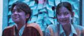 a man and a woman are sitting next to each other in front of a wall with sticky notes .