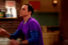 a man in a purple shirt is standing in a room