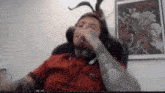 a man wearing a bunny hat is sitting in a chair covering his mouth