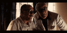 a man with glasses and a mustache is standing next to another man