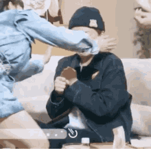 a couple of people are sitting on a couch and one of them is holding another person 's hand .