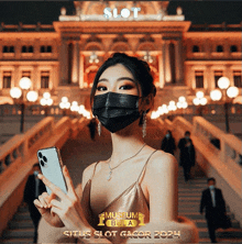 a woman wearing a mask is holding a cell phone in front of a building with the word slot on it