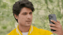 a man in a yellow jacket is taking a selfie with his phone