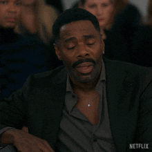 a man in a suit holds his hand to his forehead with a netflix logo below him