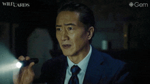 a man in a suit and tie holds a flashlight in his hand