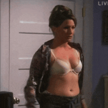a woman in a bra is standing in front of a door in a room .