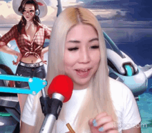 a blonde woman stands in front of a microphone with a picture of a girl in the background behind her