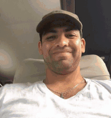 a man wearing a hat and a necklace is smiling