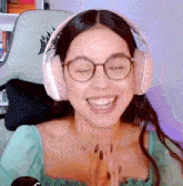 a woman wearing glasses and headphones is smiling while sitting in a chair .