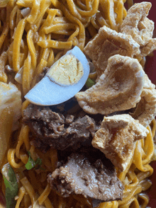 a close up of a plate of food with noodles meat and an egg