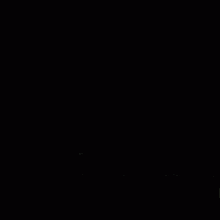 a man in a black jacket is standing on a rooftop at night looking at the city skyline .