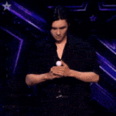 a man in a black shirt is juggling three balls with his hands .