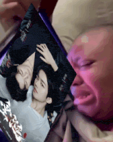 a man is crying while holding a picture of two people
