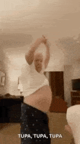 a man is dancing in a living room with his arms outstretched .