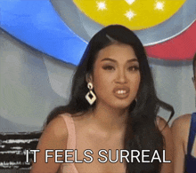 a woman says " it feels surreal " in front of a colorful background