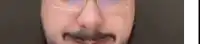 a man with a beard and glasses is making a funny face .