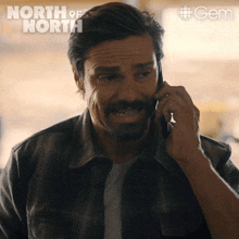 a man is talking on a cell phone with the words north of north on the bottom
