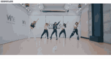 a group of women are dancing in front of a wall that says wne on it