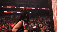 a woman in a devil costume holds a wrestling belt in front of a crowd at a raw show