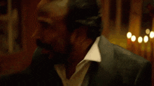 a man in a suit with blood on his face is sitting at a table .