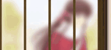 a woman in a red dress is behind bars looking out a window .