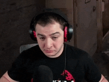 a man wearing headphones is making a face while sitting in front of a microphone .
