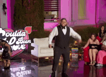 a man in a tuxedo is dancing in front of a sign that says coulda been love