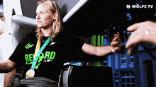 a woman with a medal around her neck is wearing a record shirt