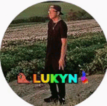 a man in a black shirt and hat is standing in a field with the name lukyn on it .
