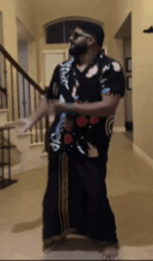a man in a hawaiian shirt is dancing in a hallway with stairs in the background