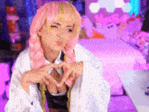 a woman in a pink wig is making a heart shape with her hands